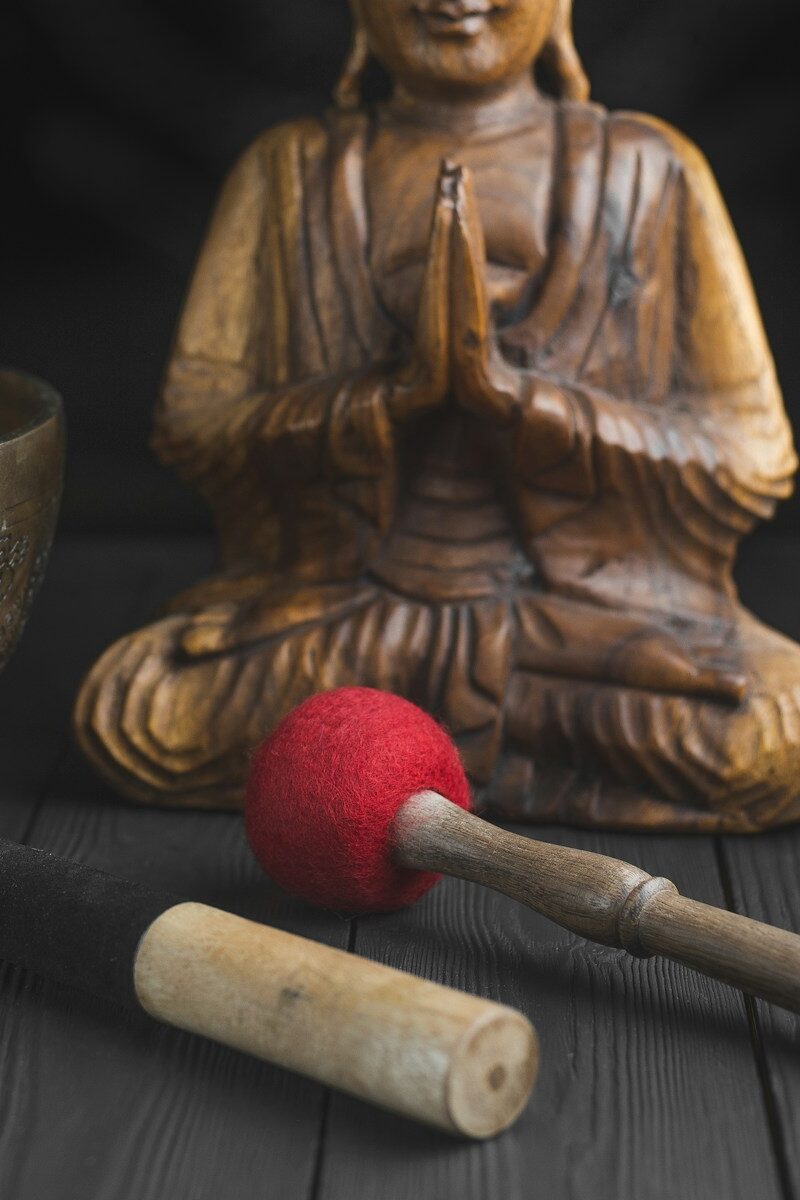 brass buddha figurine beside red and white stick